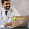 A doctor wearing a white coat smiling while working on a laptop, with a stethoscope around his neck. The desk has a notepad, pen, and some office supplies. The SwasthOPD logo is visible in the bottom right corner, and the Telecare logo is in the top left corner. The background features a minimalistic office setup with bookshelves and a small plant